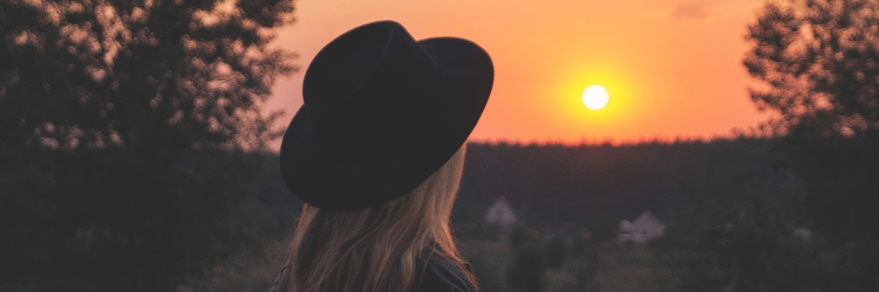 woman wearing hat watching sunrise