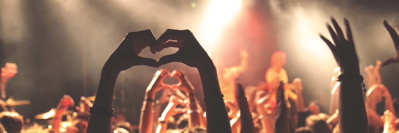 The Quiet Moments of Victory Against Depression people celebrating at concert showing love sign