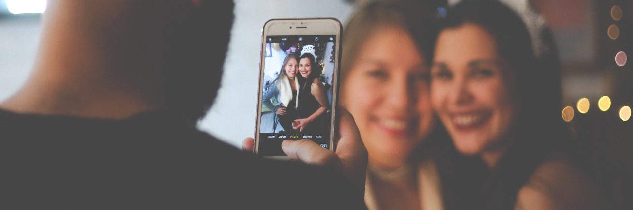 When People Think You're 'Too Functional' for Mental Illness man taking image of two smiling women on smartphone