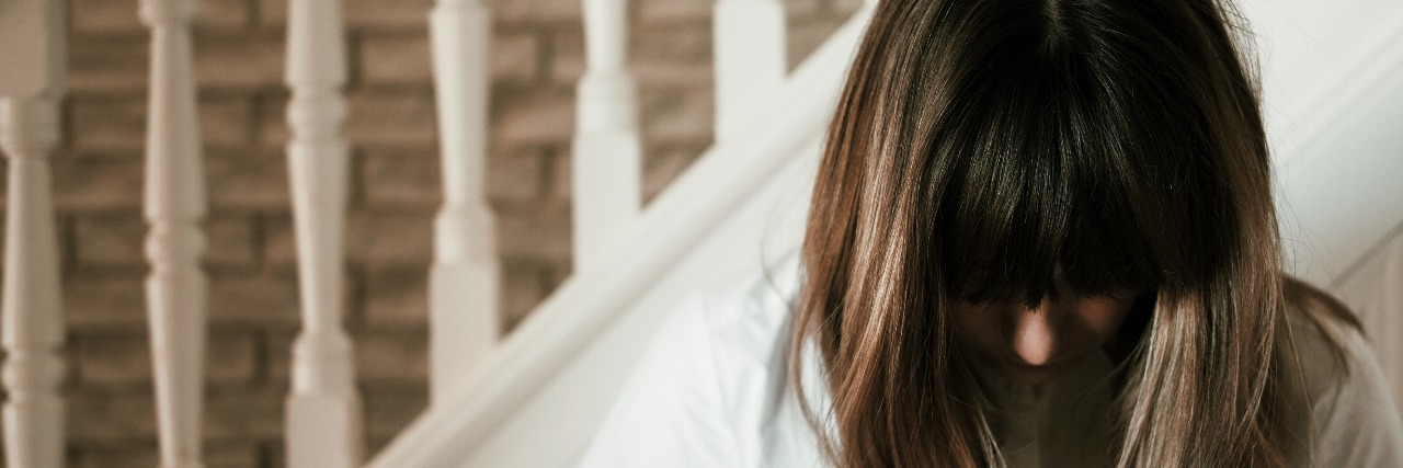 Why I'm Scared of Feeling Happiness woman standing at stairs looking down with hair covering face