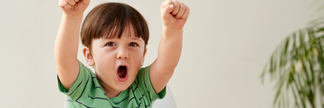 This April Accept My Family and My Son on the Autism Spectrum Happy boy wearing a green shirt, fists pumped to the sky and screaming with happiness