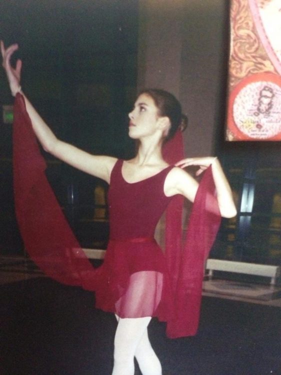 A ballerina in her red costume, dancing.