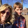 Mom and teenage son standing near trees outdoors, with building landscape in the background