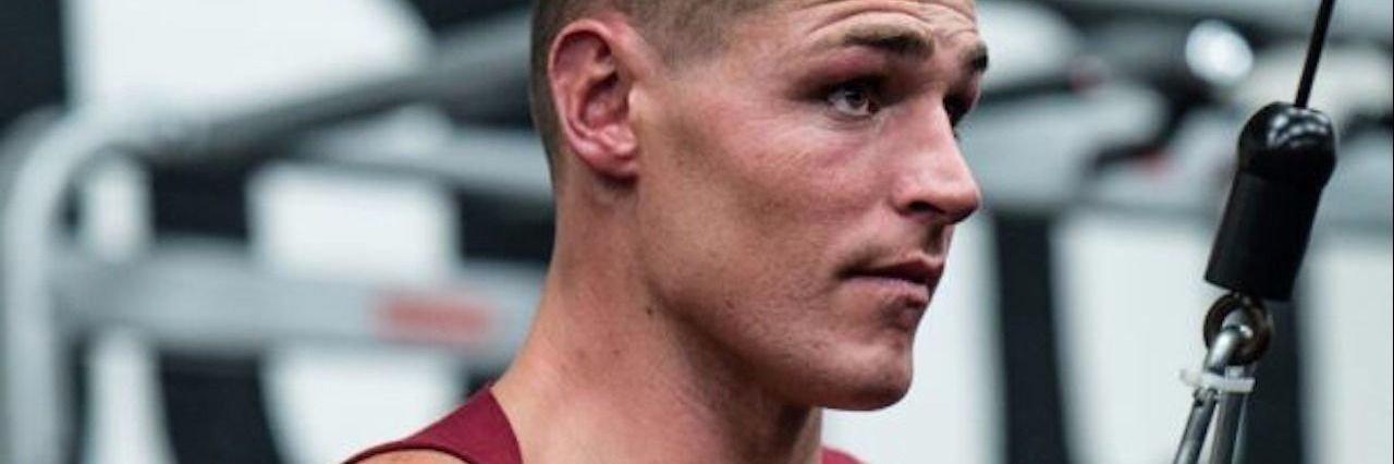 Using Fitness and Working Out to Cope With Dystonia muscular man in a red tank top working out at the gym