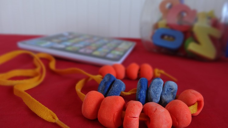 Beads made out red and blue play-doh stringed with a yellow shoe lace