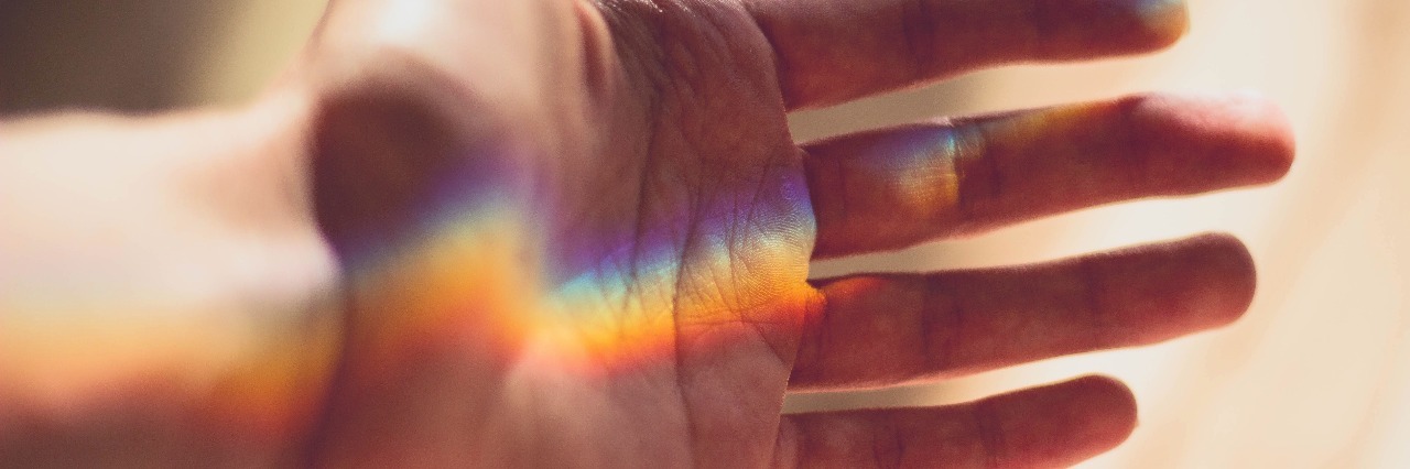 Gifts Received From Chronic Illness hand with a rainbow shining across it