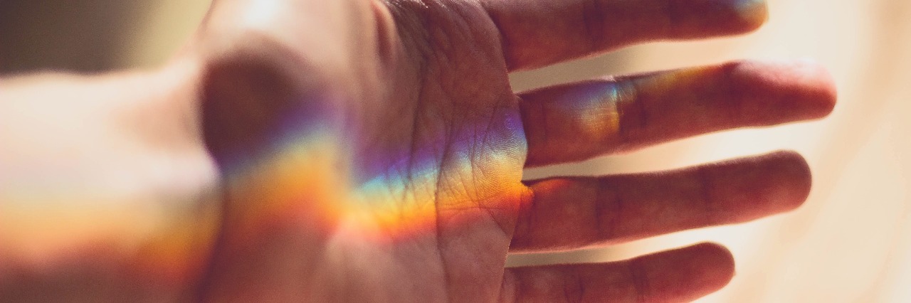 hand with a rainbow shining across it