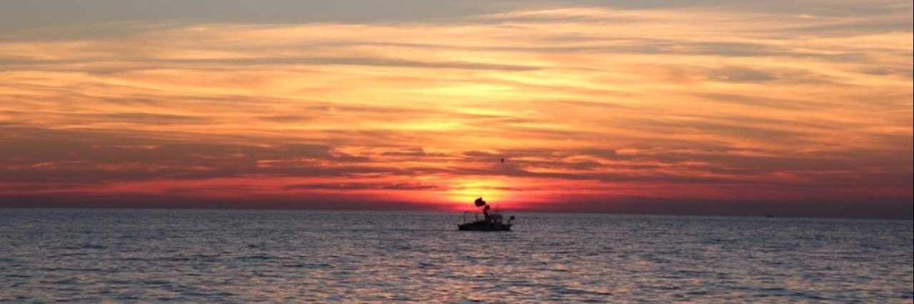 Coming Out, as Dying Boat at sea at sunset