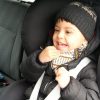 Boy in car seat in car, wearing beanie and laughing