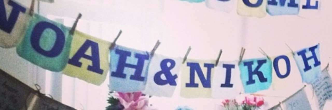 A sign in a hospital room that says [Welcome Noah and Nikoh] with a banner filled with well wishes underneath it