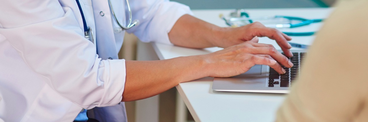 Why Learning the Science Behind My Condition Helps My Mental Health Patient having a conversation with doctor as doctor types on laptop