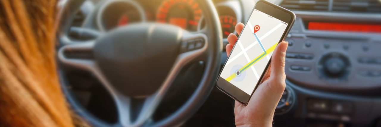 How My Life as a Mother Has Been 'Rerouted' Inside of a car, you can see red hair of a woman holding her phone open to a GPS app