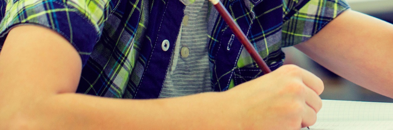 How My Stepson Described My Illness in His School Writing Assignment boy writing in notebook at desk