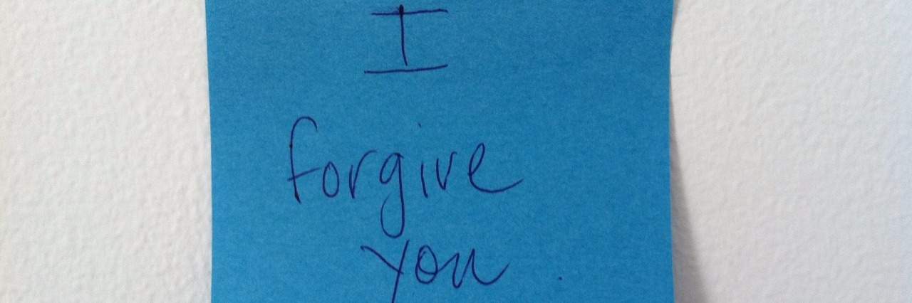 blue post it note with I forgive you written in pen and stuck to wall