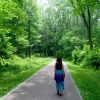 woman walking down a path through a forest
