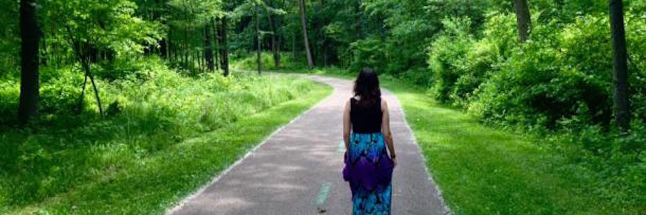 woman walking down a path through a forest