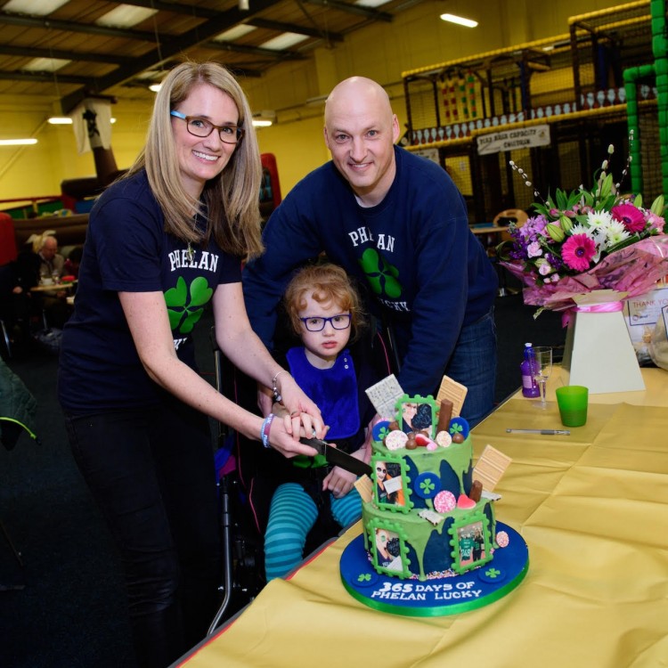 Two parents and their daughter cutting a celebration cake.