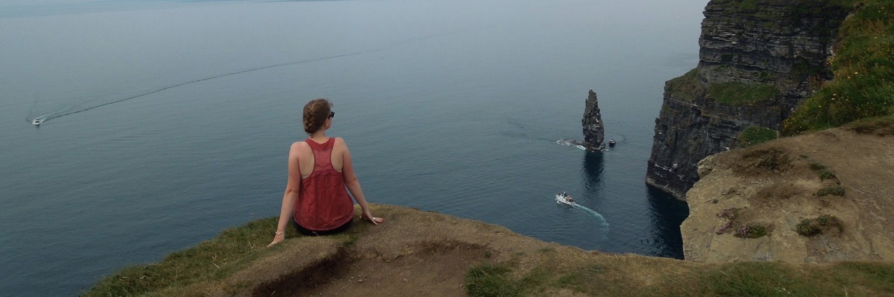 Reframing Illness: From Dwelling on Losses to Celebrating Gains Woman sits on rock, facing water