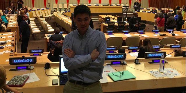 Attending World Autism Awareness Day at the United Nations as a Young Person With Autism Tom at World Autism Awareness Day 2017 at the United Nations, standing in front of tables with microphones and the stage in the background