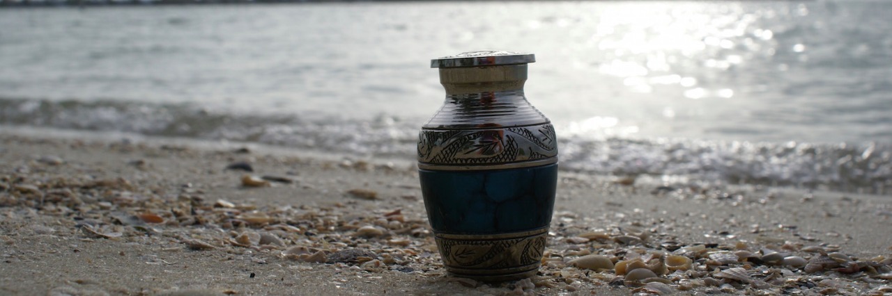 An urn on wet sand in front of a large body of water