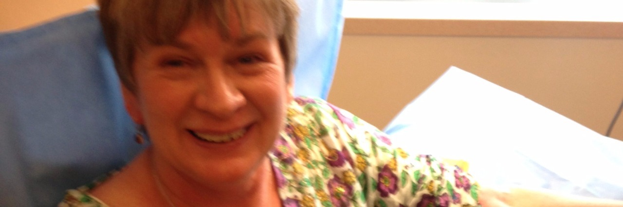 How Making Dancing Videos Helped Me Cope With Chemo and Radiation Deb wearing a flowery shirt and holding a stuffed Lama, her arm rests on the pillow as she is receiving a chemo treatment.