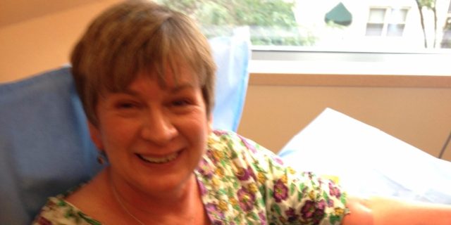 How Making Dancing Videos Helped Me Cope With Chemo and Radiation Deb wearing a flowery shirt and holding a stuffed Lama, her arm rests on the pillow as she is receiving a chemo treatment.