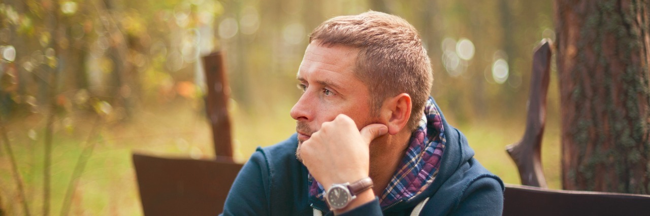 The Grief I Carry After My Father's Death Young man sitting on a park bench contemplatively