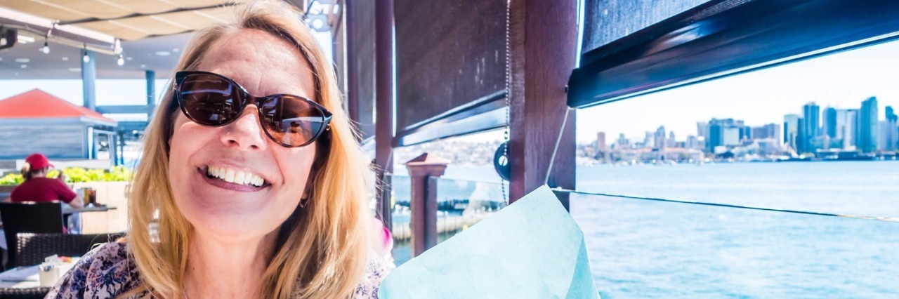 How I Balance My Emotional and Physical Well-Being With Fibromyalgia Woman wearing sunglasses, smiling by ocean