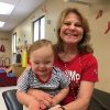 A little boy with Down syndrome sitting on his therapist's lap for a photo