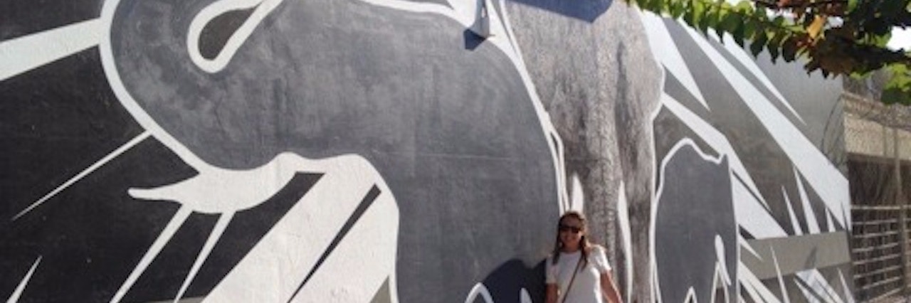 girl standing next to painting of elephants