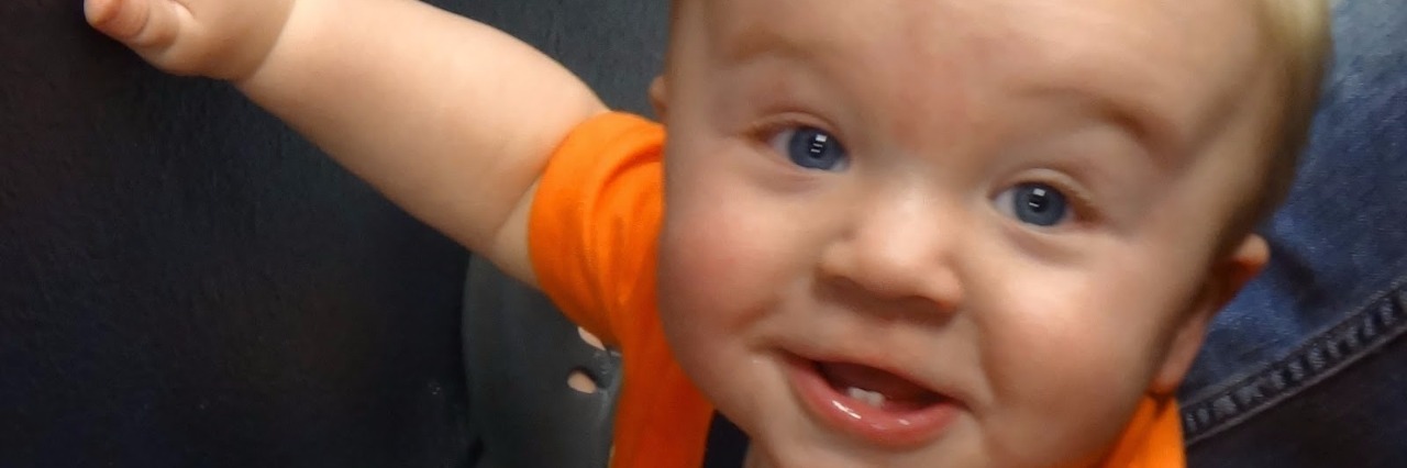 Three Years After Losing My Baby to SIDS Baby with one hand raised, wearing an orange shirt