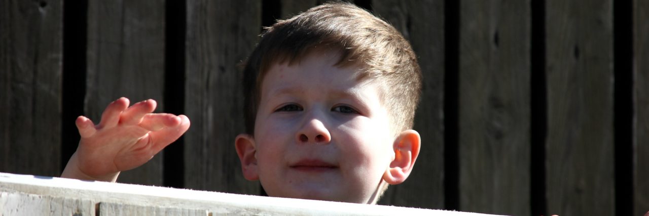 Raising Awareness of Undiagnosed Children's Day Brody peeking over a fence.