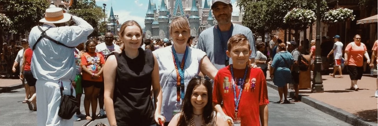 family of five posing at disneyland in front of the castle