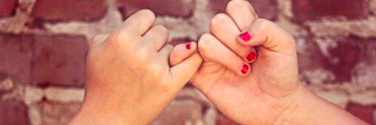 When My Anxiety Stops Me From Spending Time With Friends Two hands locking pinkies in front of a brick wall