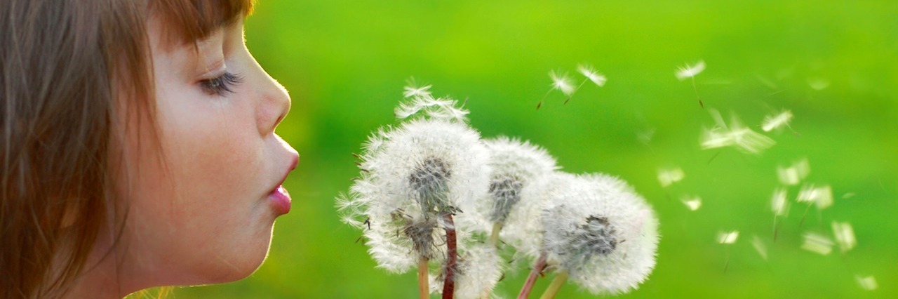 I'm Worried My Daughter Will Get My Mental Illness A young girl blowing on dandelions