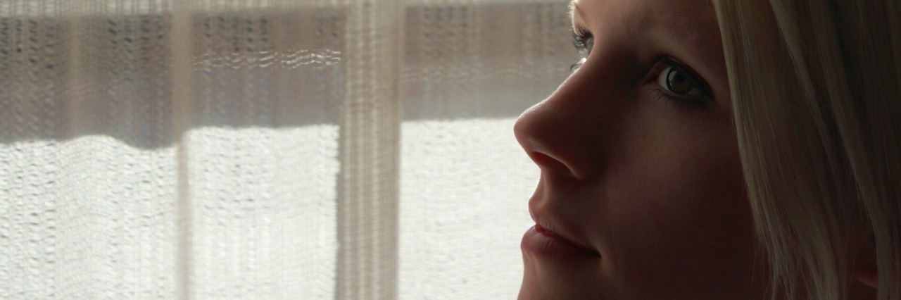 Young woman standing by window, close-up
