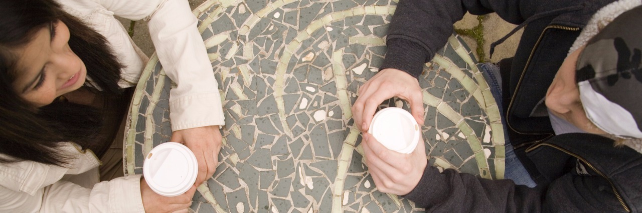 High angle view of a young couple holding cups of cappuccino