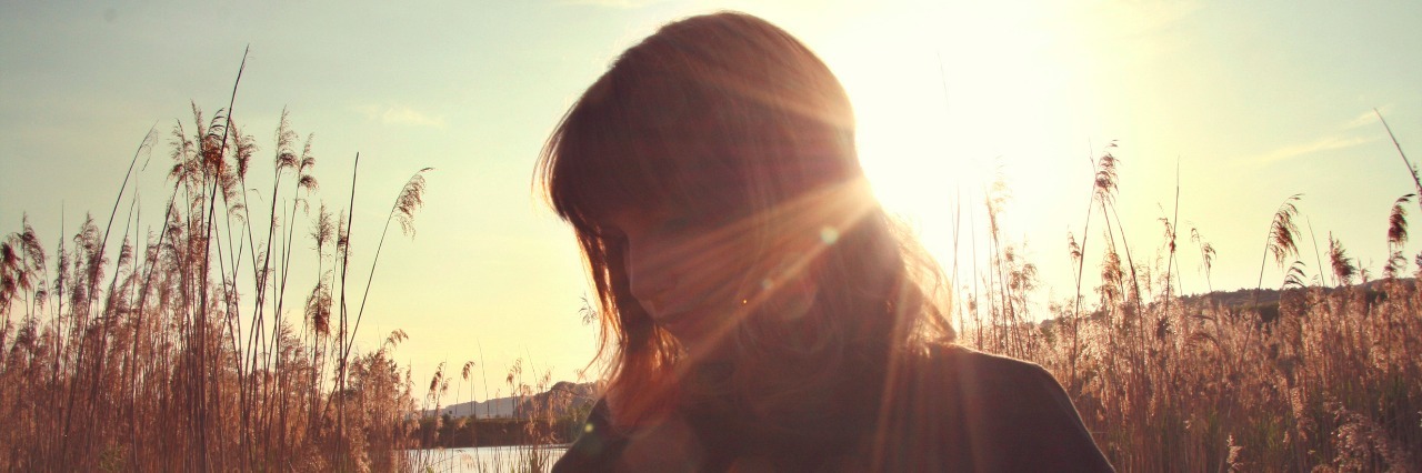 How I View Success With Lyme Disease and Autoimmune Disease woman in field with sun behind her