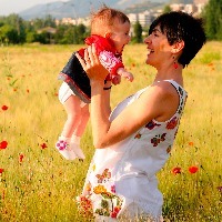 Woman smiling in a poppy field with her baby girl.