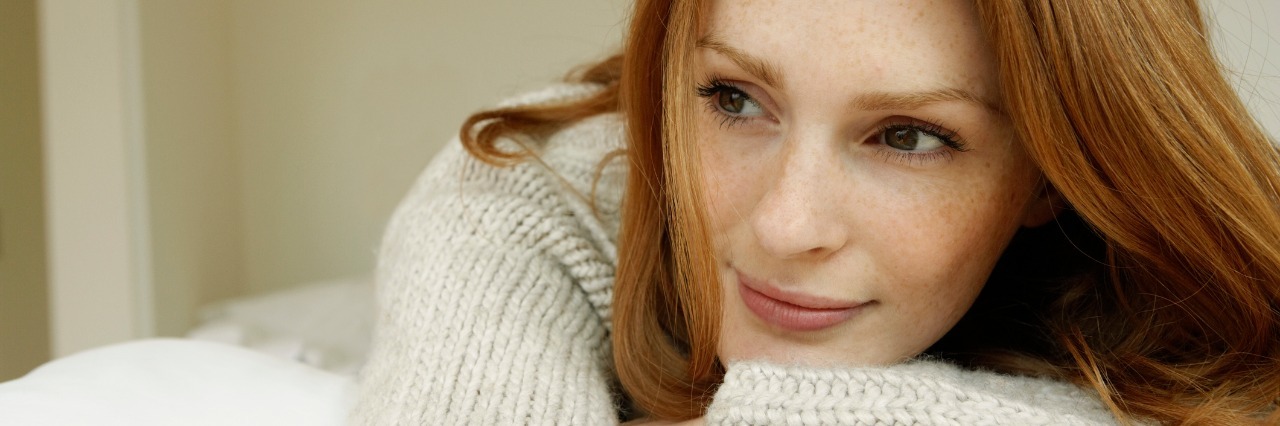 Finding Joy and Contentment With Chronic Illness woman with red hair leaning on her arms and smiling