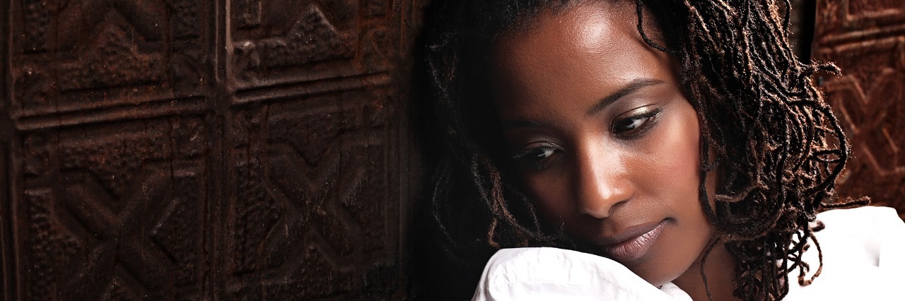 My Recovery Journey Through Postpartum Depression young black woman in white shirt depressed against wooden wall