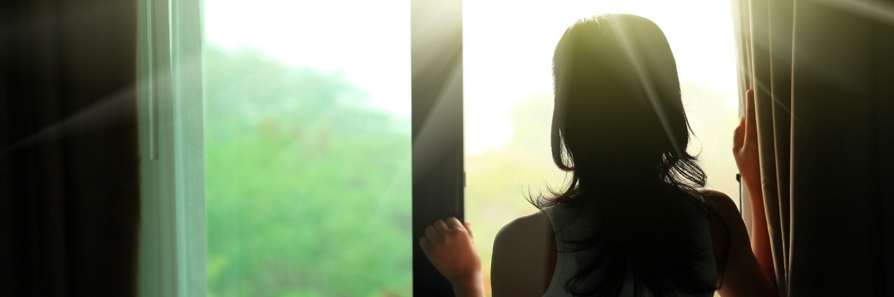 girl opening curtains in a bedroom