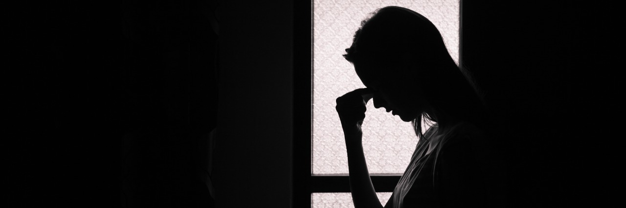 How Mental Health Struggles Build Up With Lupus Depressed young woman in a dark room