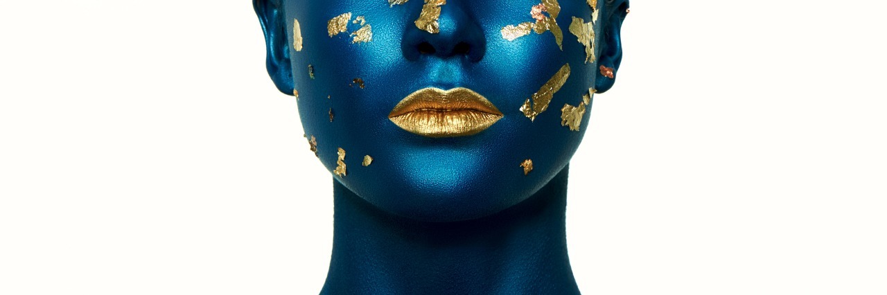 When Physical and Mental Illnesses Collide Woman painted blue, with gold specks on face and fold lipstick.