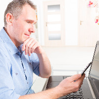 Man with hearing aid working with laptop and mobile phone.