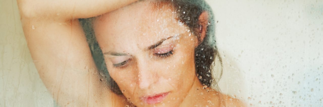 stressed woman leaning on weeping glass shower door