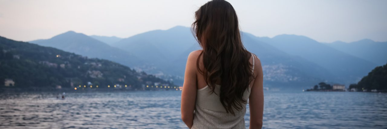 Scoliosis Stigma and Invisible Disability Woman sitting by a lake.