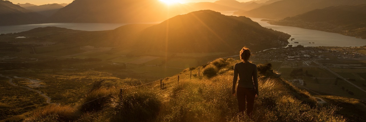 relaxed woman in new zealand mountains at sunset