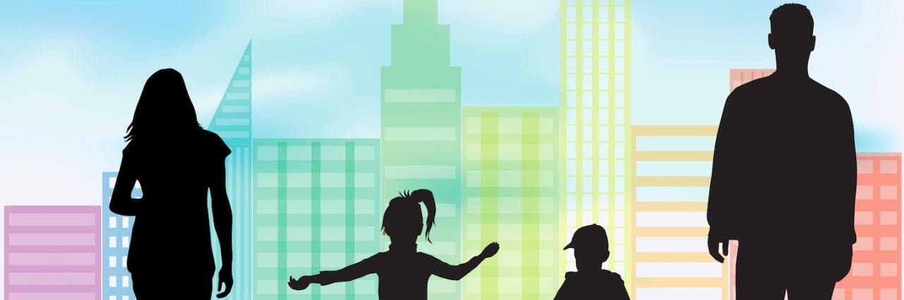 Silhouettes of man, woman, boy and girl on grass in front of city buildings