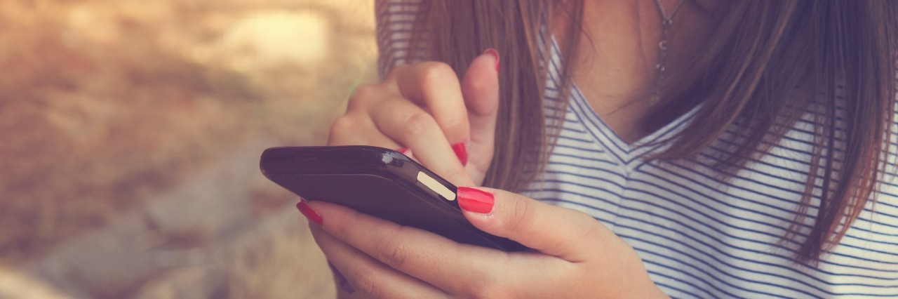 Dear Friend Who I Fear Is Tired of Giving Me Reassurance woman texting on phone outdoors